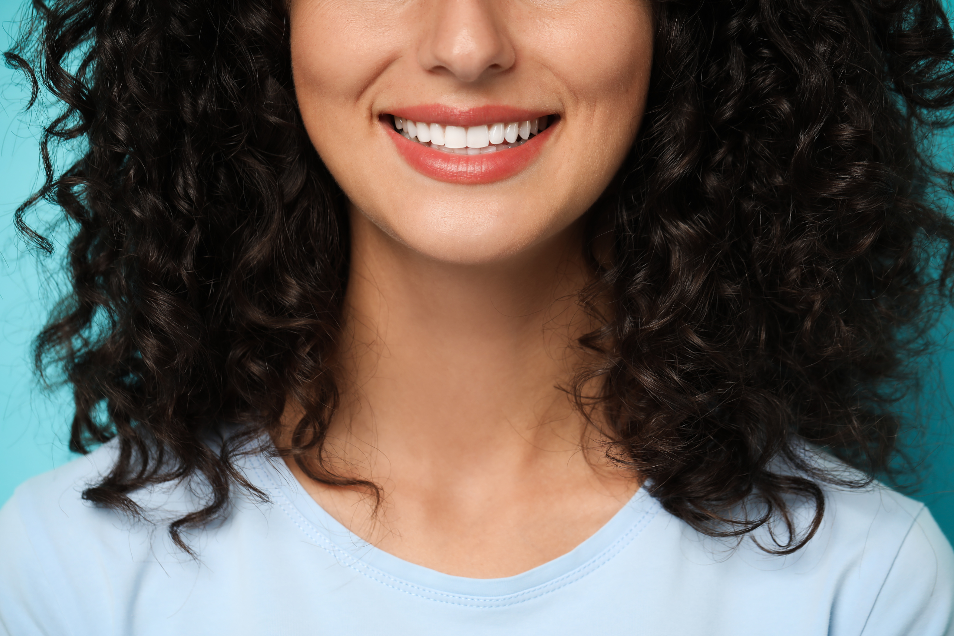 Donna sorridente con denti bianchi e ben allineati, esempio di sorriso curato dopo valutazione per faccette dentali